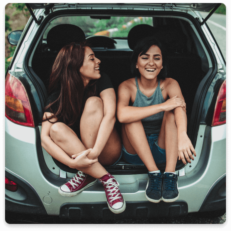 Two women enjoying a road trip in their newly insured car